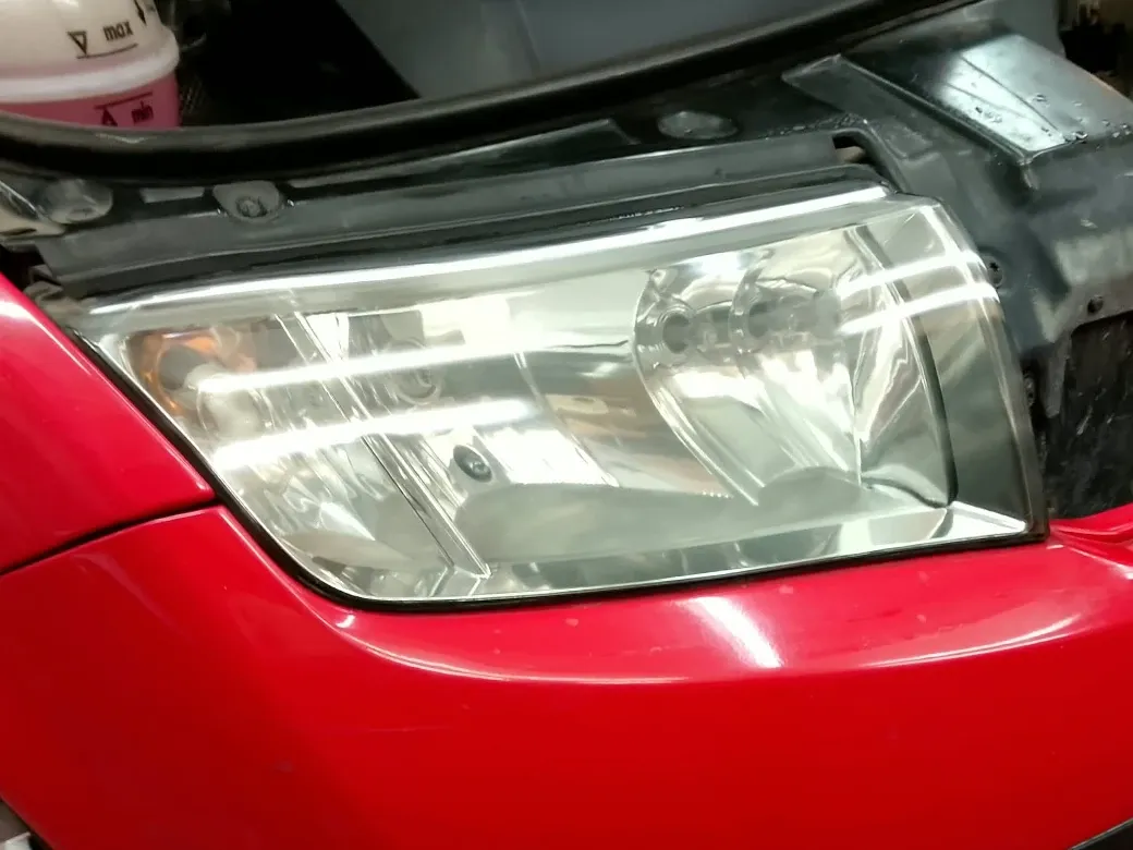 Stejný světlomet červeného automobilu po renovaci.