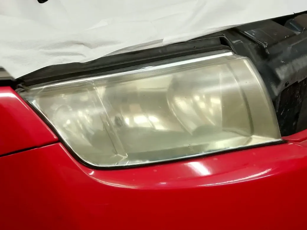 Světlomet červeného automobilu před renovací.